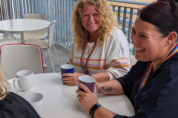 Two people talking and smiling at a table with coffee cups