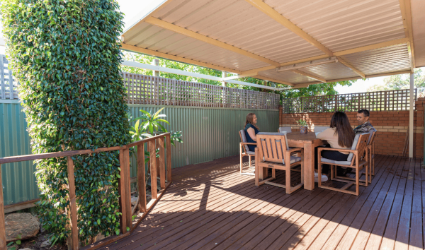 Three people at a table on a patio talking