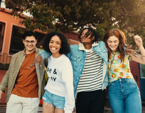 4 young people walking with arms around each other smiling