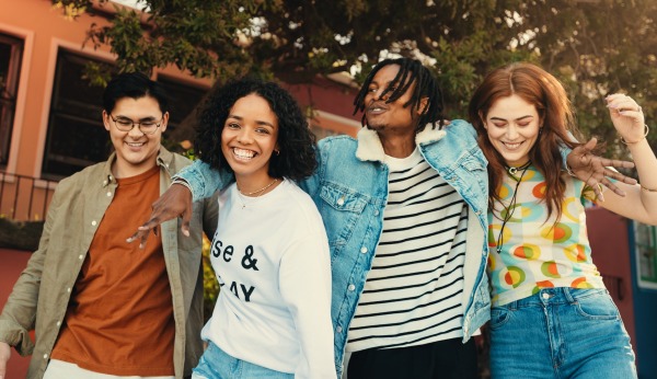 4 young people walking with arms around each other smiling