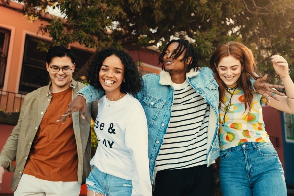 4 young people walking with arms around each other smiling