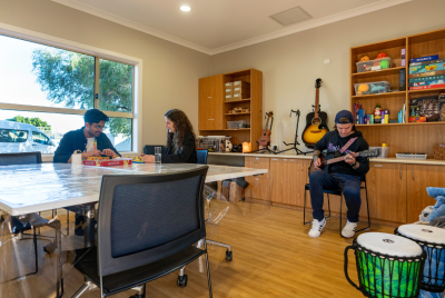 3 people in a music room playing guitar and board games