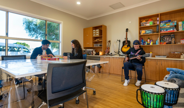 3 people in a music room playing guitar and board games