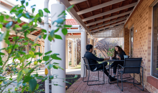 two people outside drinking coffee and talking