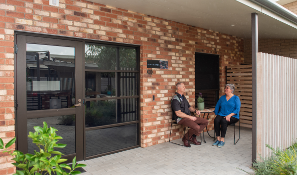 two people sitting and talking outside a building entrance