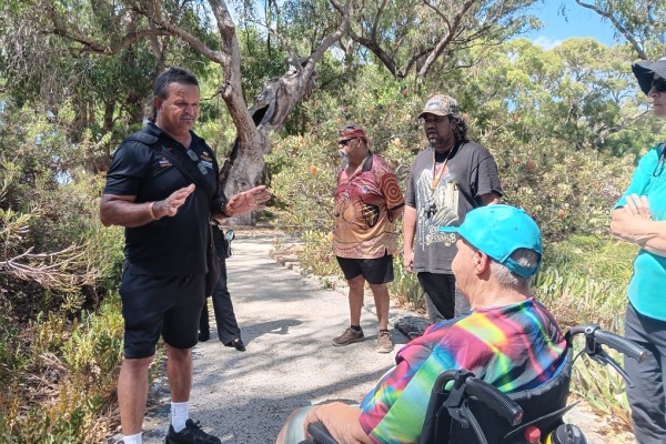 A group of Aboriginal people talking on a path through bushland
