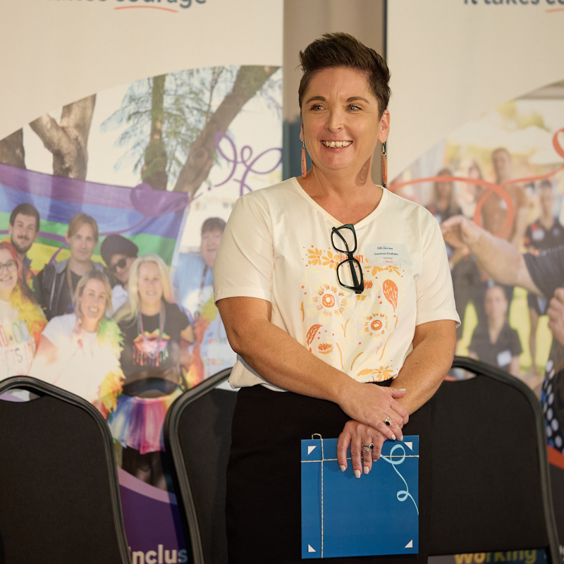 woman standing on stage smiling holding an award folder