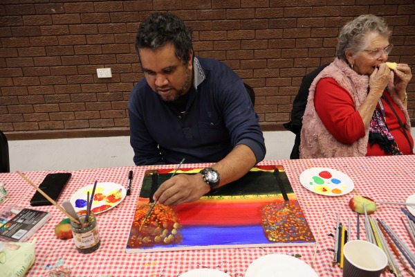 A man sitting at a table and painting as part of Heart and Soul